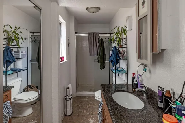 a bathroom with a granite countertop sink toilet and shower