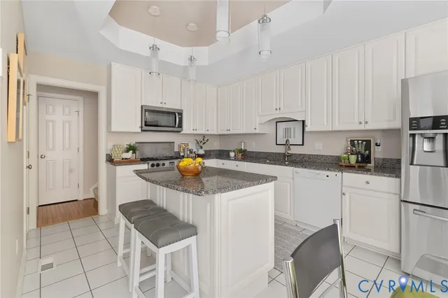 a kitchen with granite countertop a sink stove and white cabinets