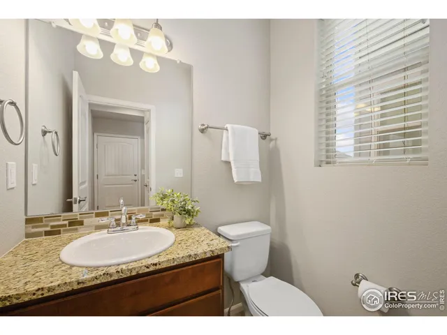 a bathroom with a granite countertop sink a mirror and a toilet
