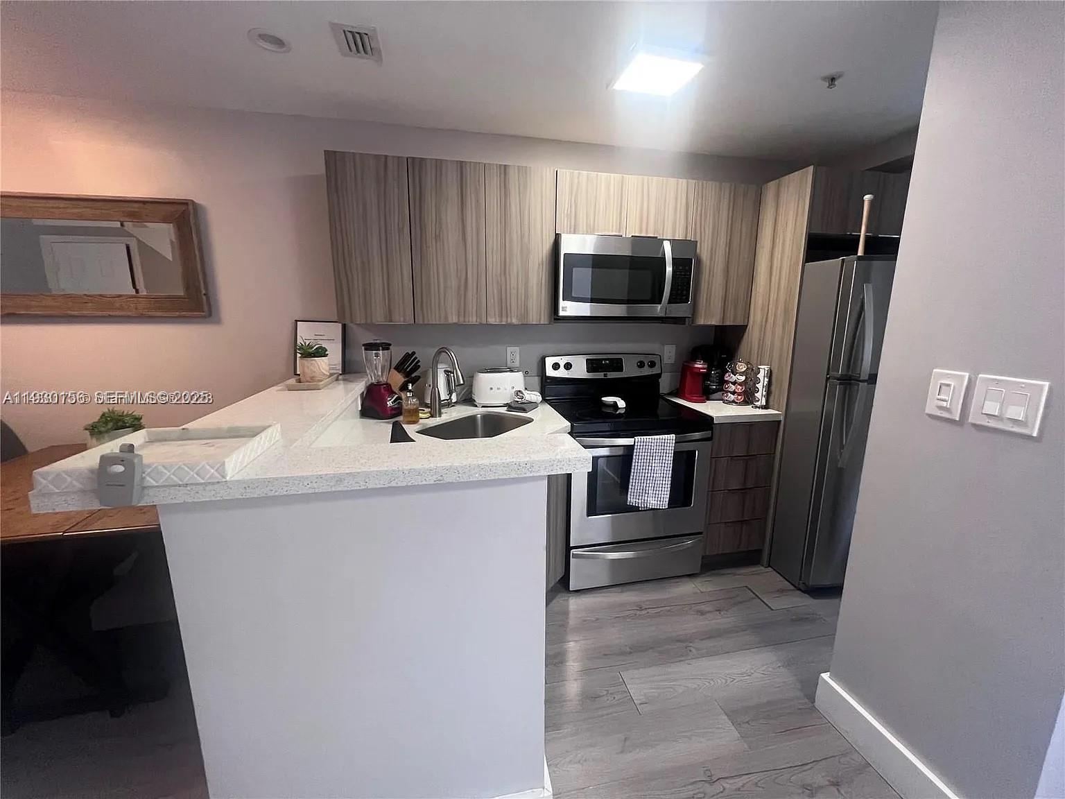 821 Southwest 2nd Street, Unit 2 Miami, FL 33130 - Photo 2 of 12 a kitchen with sink a microwave a refrigerator and cabinets