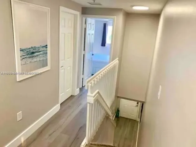 a view of a hallway with wooden floor and staircase