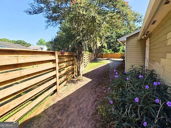 a view of a backyard with plants and large trees
