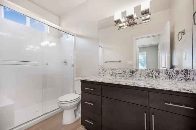 a bathroom with a granite countertop sink toilet a mirror and shower