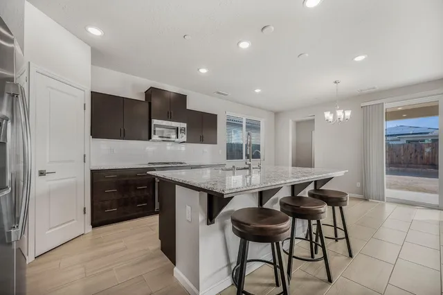 a kitchen with stainless steel appliances kitchen island granite countertop a stove top oven a sink a dining table and chairs with wooden floor