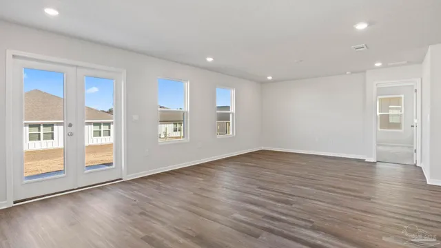 a view of an empty room with glass door and wooden floor