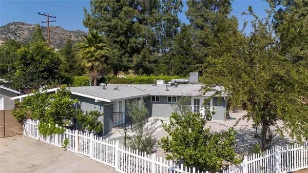 a view of a house with a small yard and wooden fence