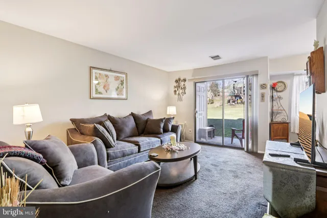 a living room with furniture and a dining table with bookshelf