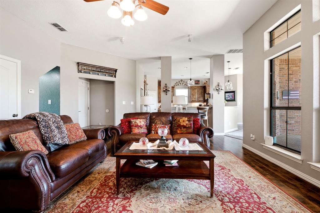 600 Aspen Street Pilot Point, TX 76258 - Photo 6 of 39 Spacious living area featuring wood-finish flooring, neutral wall tones, a ceiling fan with integrated lighting, and multiple windows including a transom window