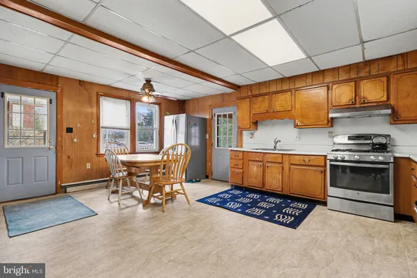 a kitchen with a stove a refrigerator and chairs