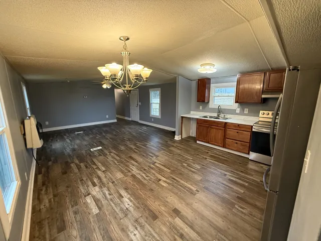 a view of a kitchen with a sink wooden cabinet fire place and a refrigerator