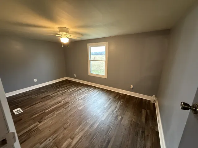 an empty room with wooden floor and windows