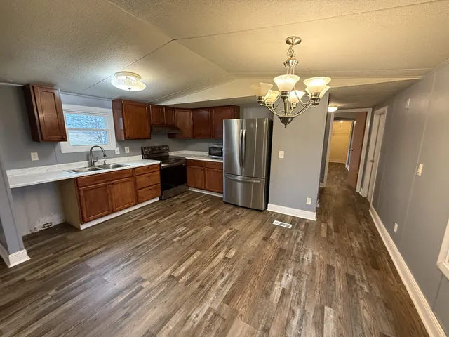 a view of a kitchen with a sink wooden cabinet and stainless steel appliances