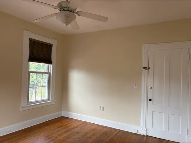 an empty room with wooden floor closet and windows