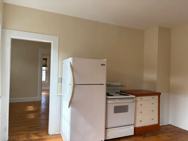 a white refrigerator freezer and a wooden floor