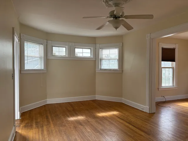 a view of empty room with wooden floor and fan