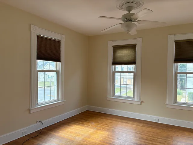 a view of an empty room with a window and wooden floor