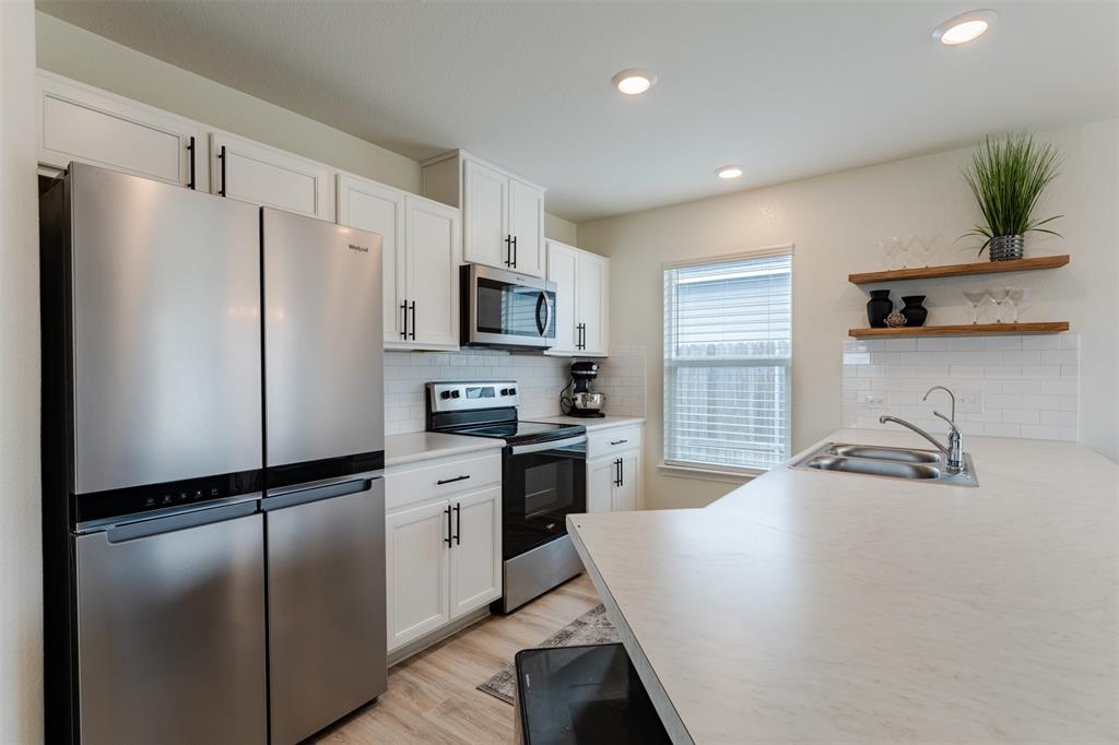 308 McLintock Road Jarrell, TX 76537 - Photo 1 of 1 a kitchen with a refrigerator a sink a stove a microwave a counter top space and cabinets