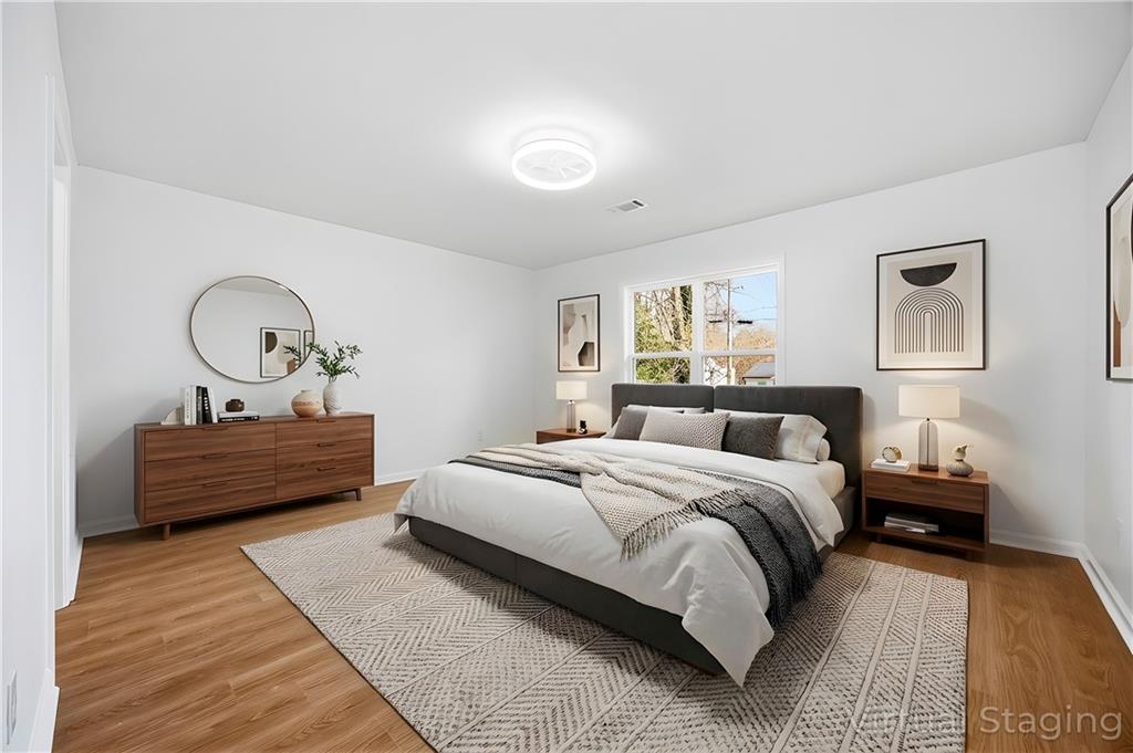 1775 Hadlock Street Southwest Atlanta, GA 30311 - Photo 16 of 27 a bedroom with a bed a potted plant on dresser and a wooden floor