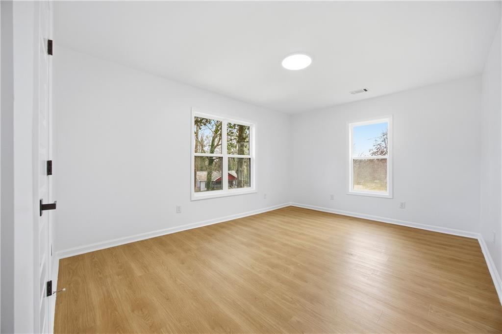 1775 Hadlock Street Southwest Atlanta, GA 30311 - Photo 19 of 27 an empty room with wooden floor and windows