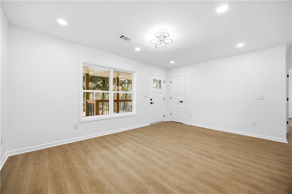 1775 Hadlock Street Southwest Atlanta, GA 30311 - Photo 5 of 27 an empty room with wooden floor and windows