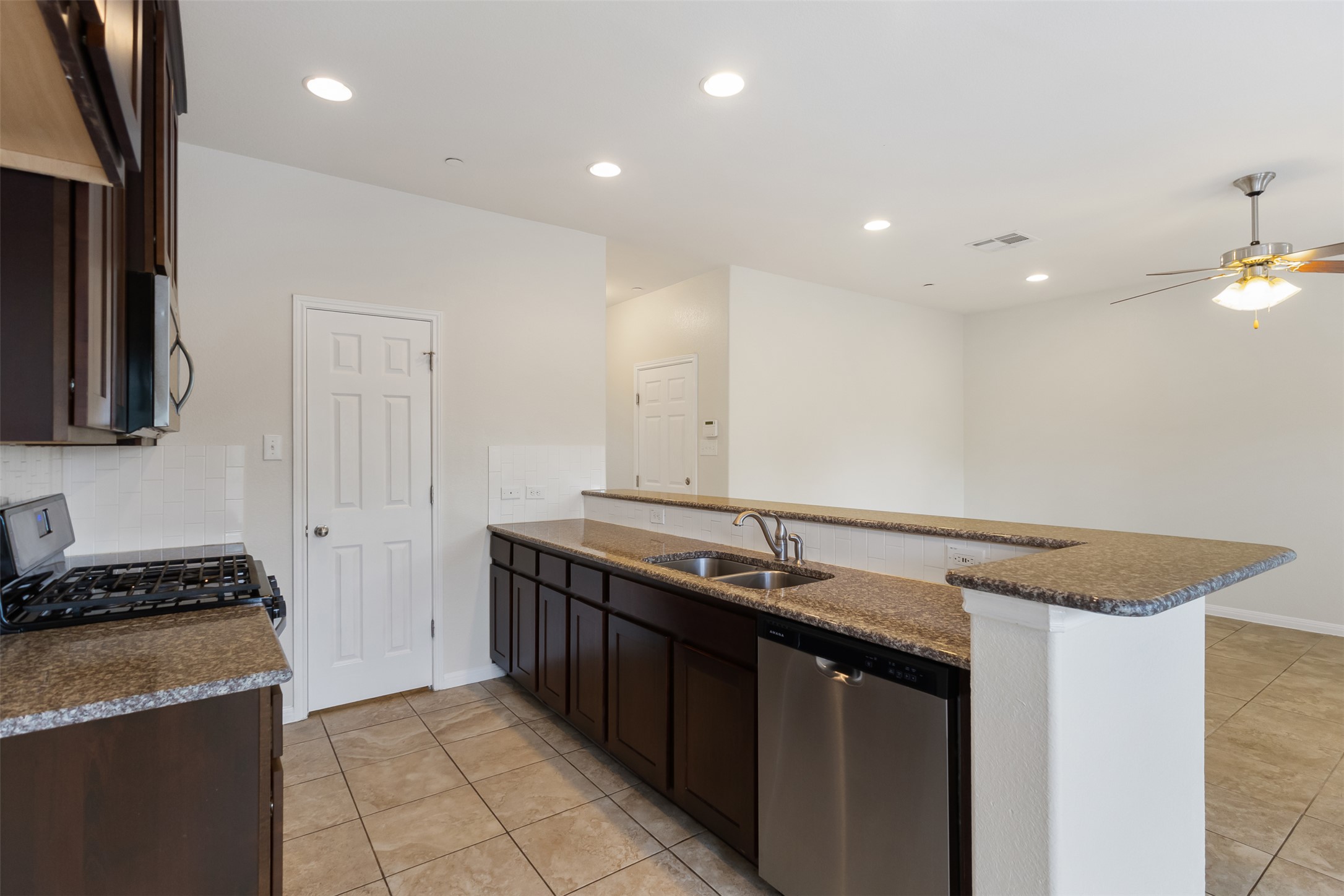 1510 Catalan Road, Unit 602 Austin, TX 78748 - Photo 11 of 36 Kitchen with stainless steel appliances, a peninsula, light tile patterned floors, decorative backsplash, and dark brown cabinets