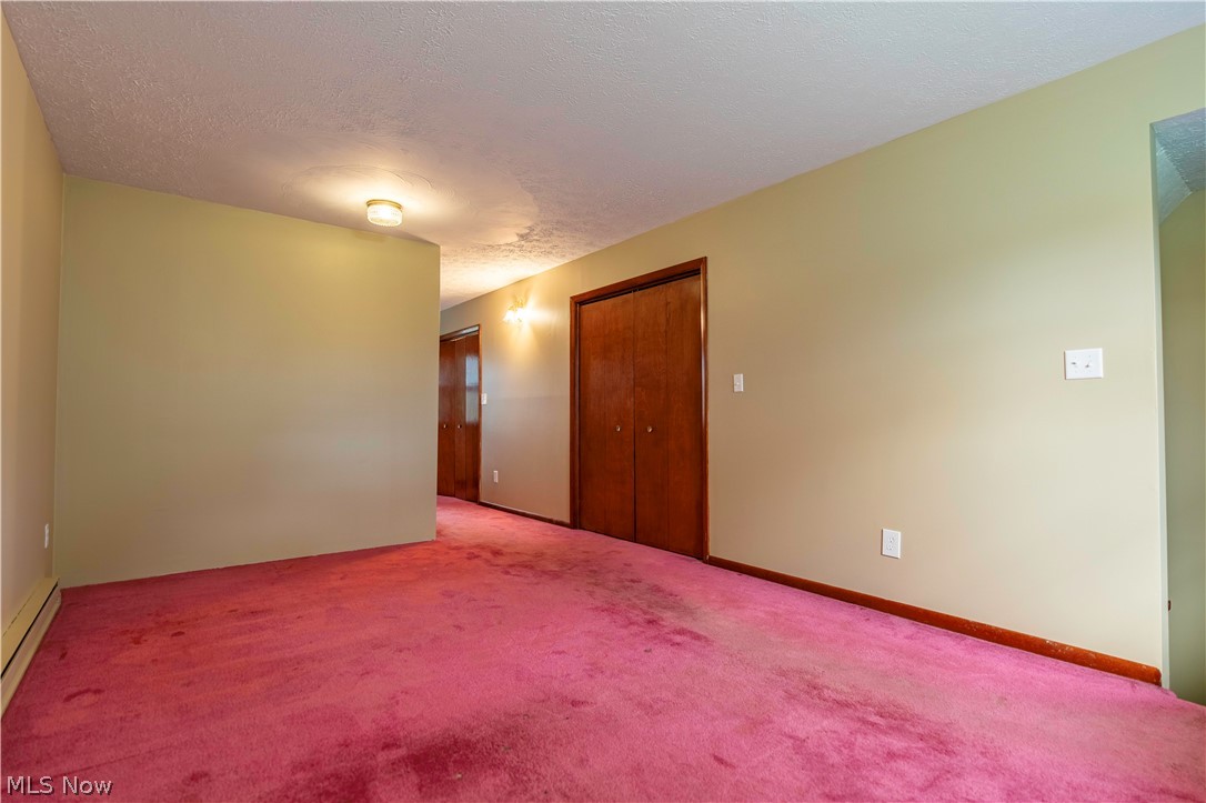 2159 Portage Line Road Mogadore, OH 44260 - Photo 31 of 35 Spare room featuring light carpet, a baseboard heating unit, and a textured ceiling