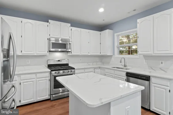 a kitchen with white cabinets stainless steel appliances and sink