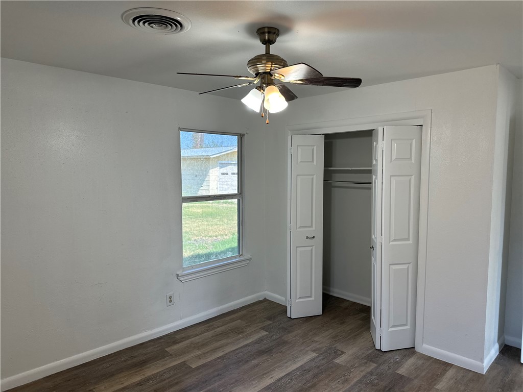 317 Redwood Drive Mathis, TX 78368 - Photo 22 of 26 an empty room with wooden floor chandelier fan and windows