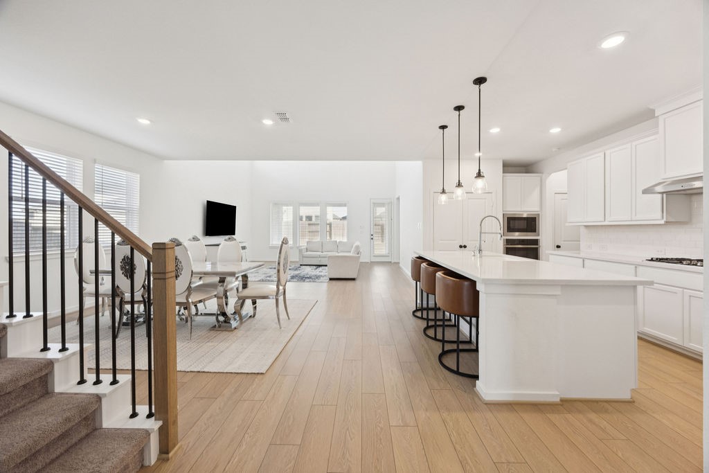 8922 Riverton Rdg Road Cypress, TX 77433 - Photo 4 of 25 a kitchen with stainless steel appliances kitchen island granite countertop a stove top oven a sink a dining table and chairs with wooden floor