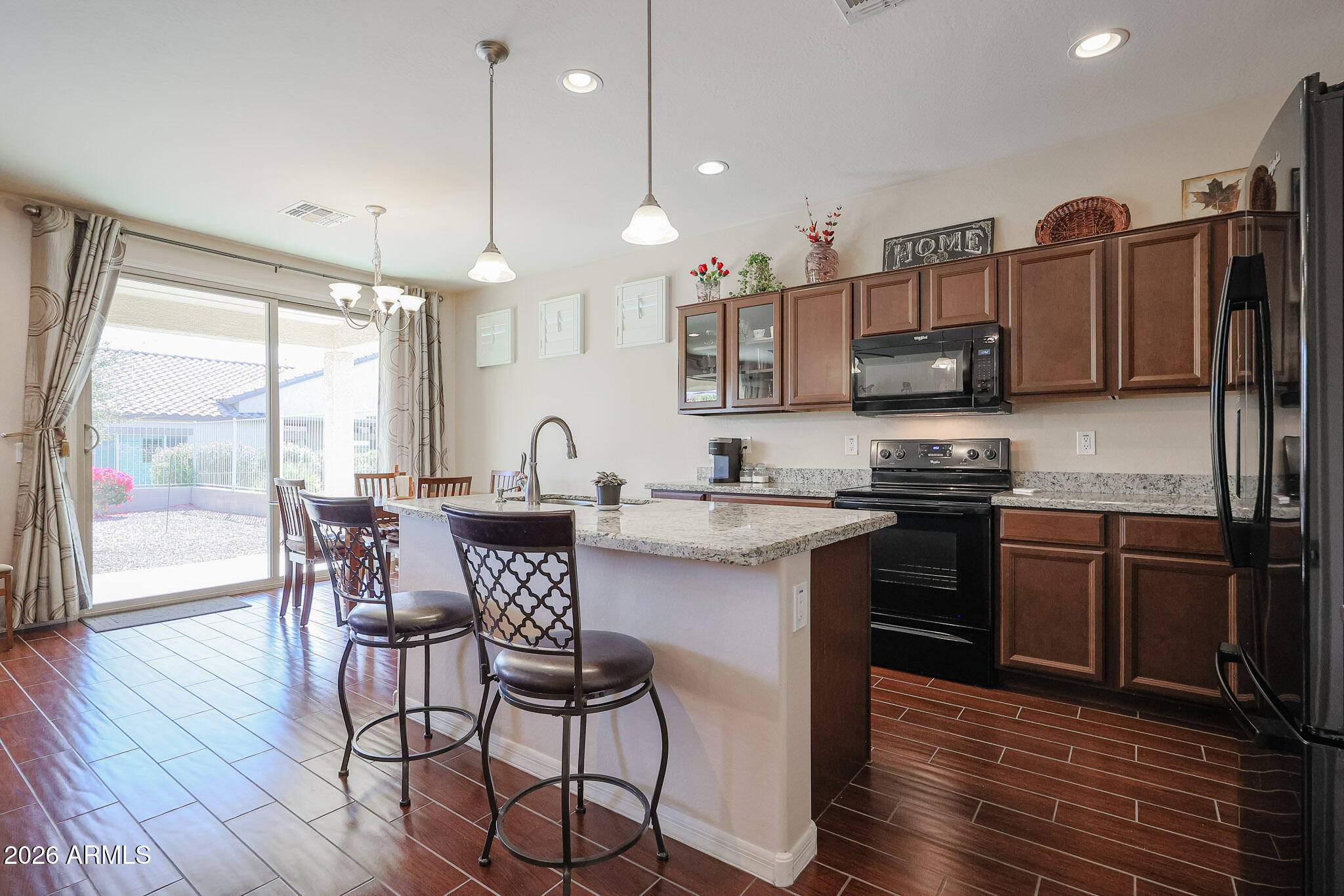 17545 West Fairview Street Goodyear, AZ 85338 - Photo 13 of 55 a kitchen with stainless steel appliances granite countertop a stove a sink a microwave a dining table and chairs with wooden floor