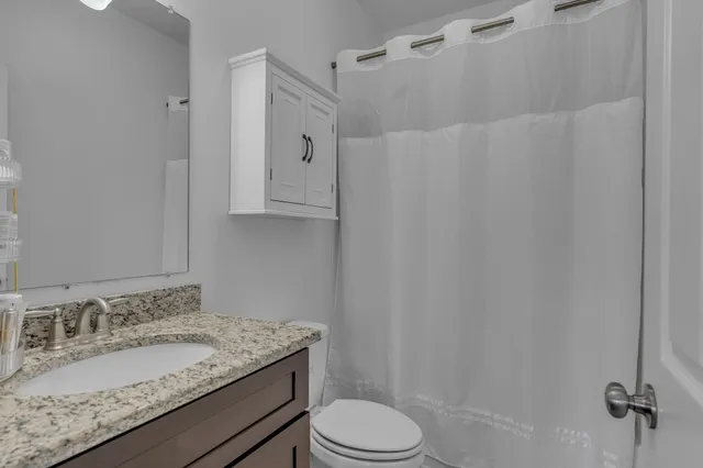 a bathroom with a granite countertop sink toilet and shower