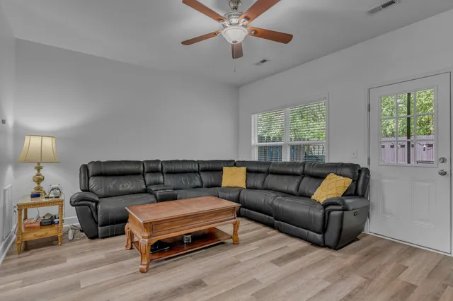 a living room with furniture a ceiling fan and a window