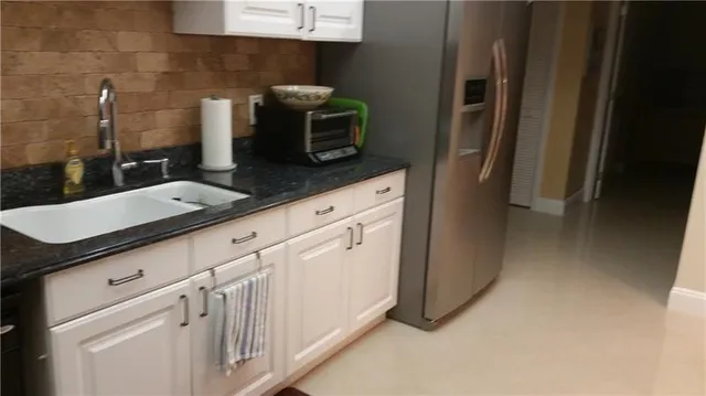 a kitchen with granite countertop white cabinets and stainless steel appliances