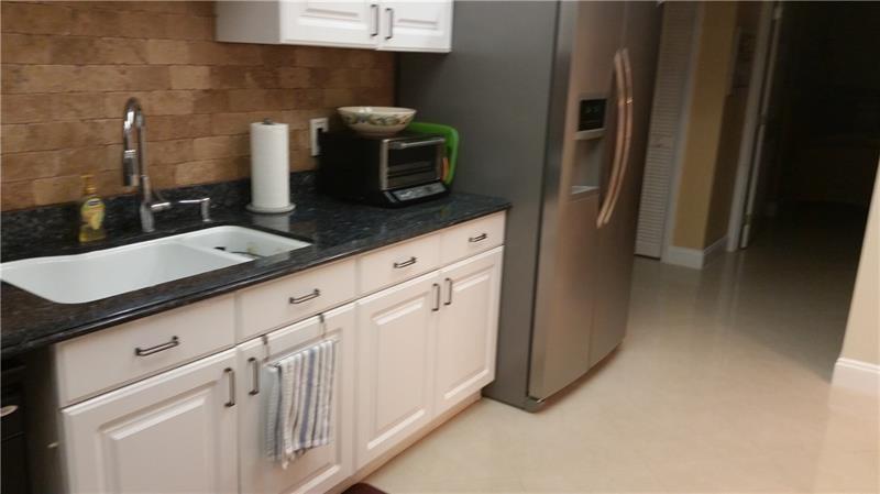 625 Oaks Drive, Unit 704 Pompano Beach, FL 33069 - Photo 2 of 10 a kitchen with granite countertop white cabinets and stainless steel appliances