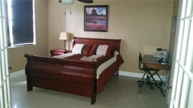 a bed sitting in a bedroom next to a window with chair