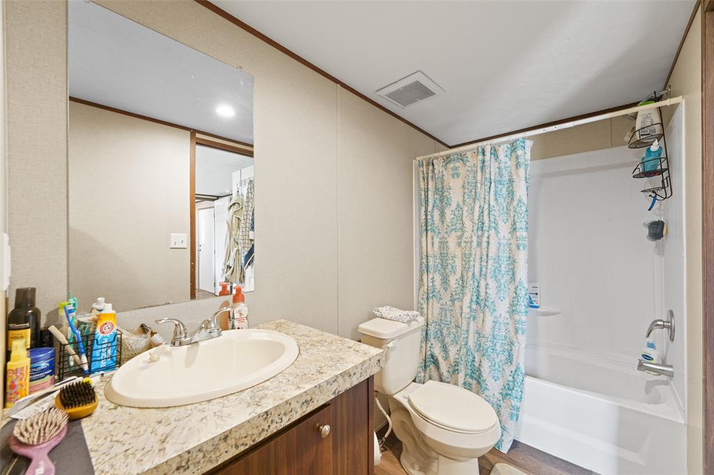0 Ewing Road Ferris, TX 75125 - Photo 20 of 29 Bathroom featuring a vanity with an integrated sink, a speckled countertop, and wood-finish cabinetry