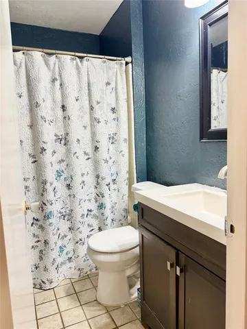 a bathroom with a granite countertop toilet and a shower curtain