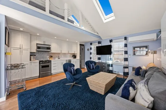 a living room with furniture a flat screen tv and kitchen view
