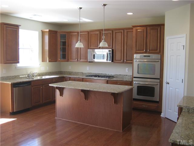229 Forbes Road, Unit LOT62 Wake Forest, NC 27587 - Photo 2 of 12 Open kitchen with 36" gas cooktop and double wall ovens. 42" raised panel kitchen cabinets in maple with New Venetian Gold granite counters.