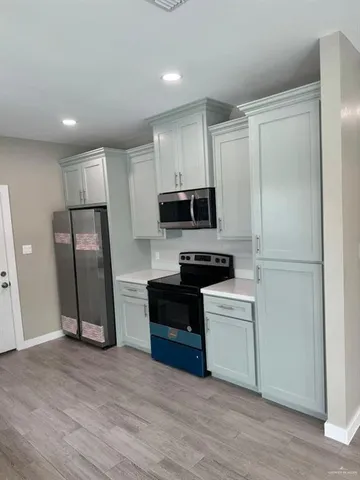 a view of a kitchen with a sink and dishwasher stove a refrigerator with wooden floor
