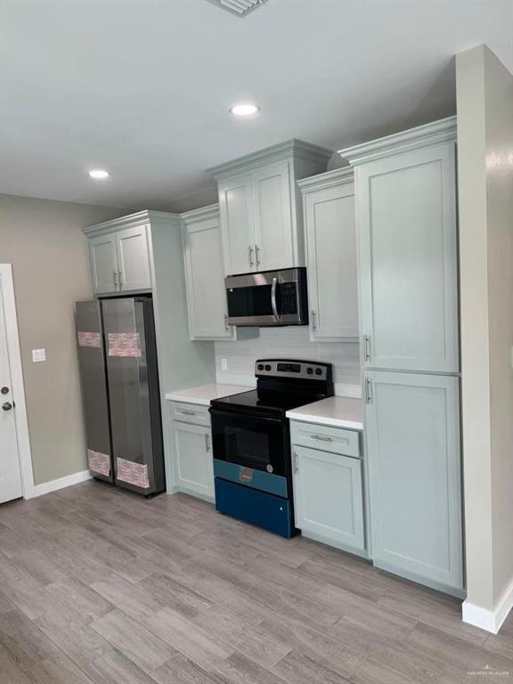 5609 Nightingale Avenue, Unit 2 Mission, TX 78573 - Photo 5 of 13 a kitchen with a refrigerator a stove top oven and wooden floor
