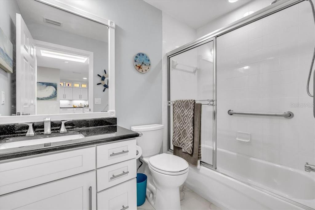 1260 Rio De Janeiro Avenue, Unit 102 Punta Gorda, FL 33983 - Photo 30 of 46 a bathroom with a granite countertop sink a toilet a mirror and shower