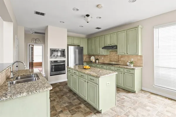 a kitchen with granite countertop a sink stove refrigerator and cabinets