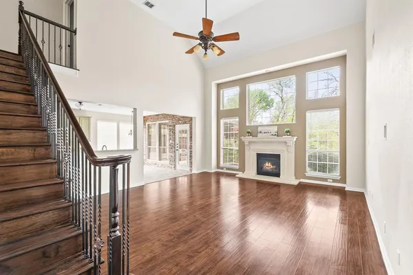 a view of an empty room with wooden floor fireplace and a window