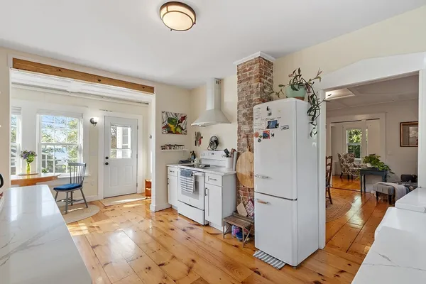 a kitchen with a refrigerator a stove top oven a dining table and chairs