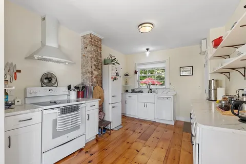 a kitchen with a white stove cabinets and window