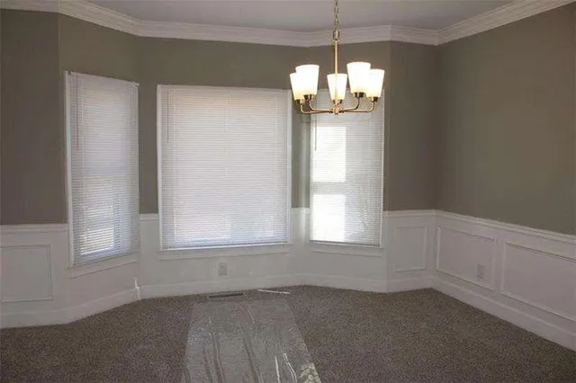 an empty room with chandelier fan and windows