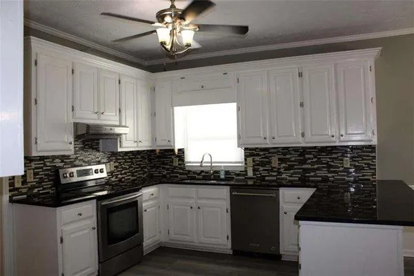 a kitchen with granite countertop white cabinets and black appliances