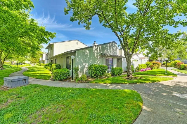 a view of a house with a yard and table and chairs under an umbrella