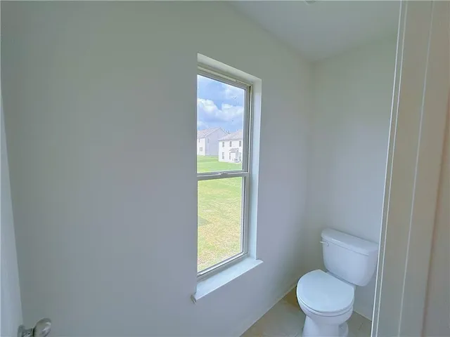 a white toilet sitting in a bathroom next to a window